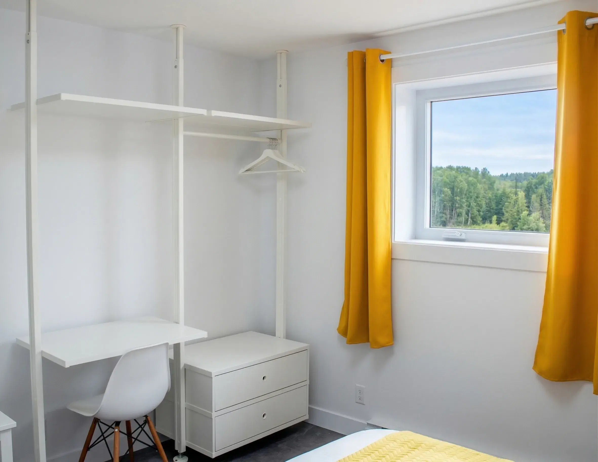 Chambre aux rideaux jaunes avec bureau et vue sur la forêt
