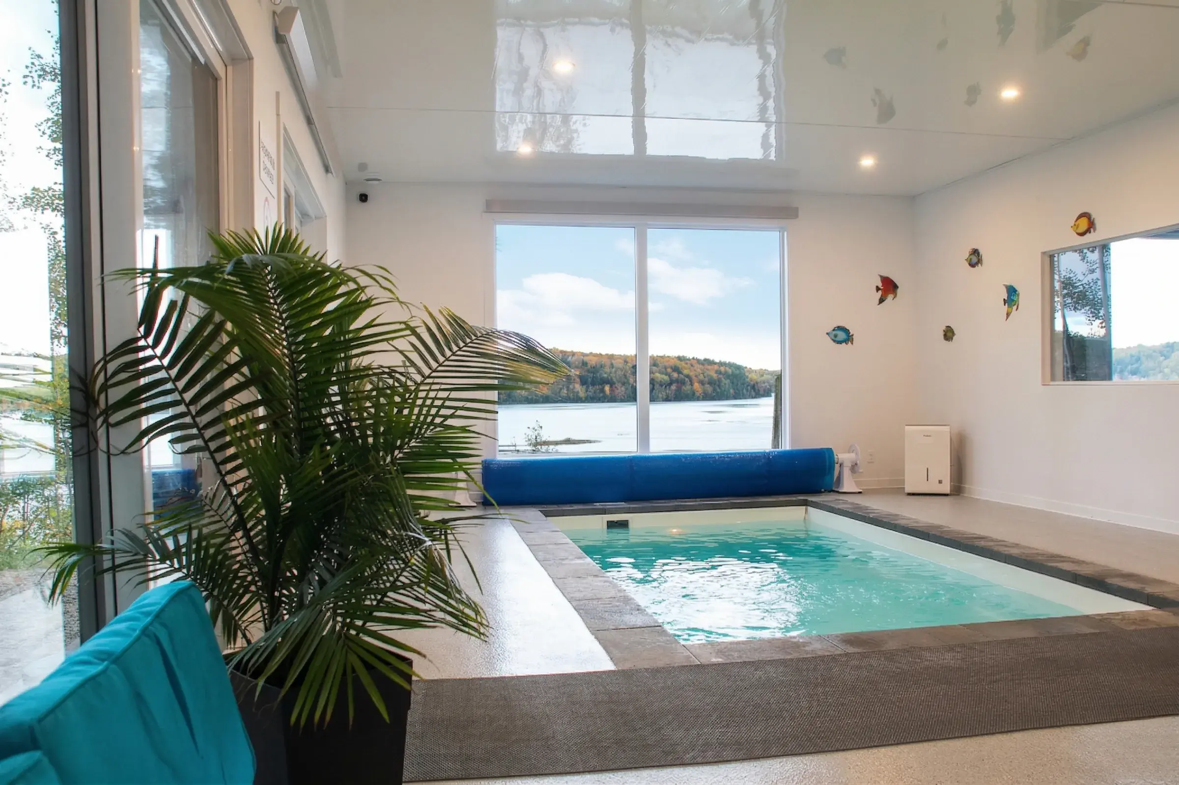 Piscine intérieure avec spa encastré et grande fenêtre sur la rivière
