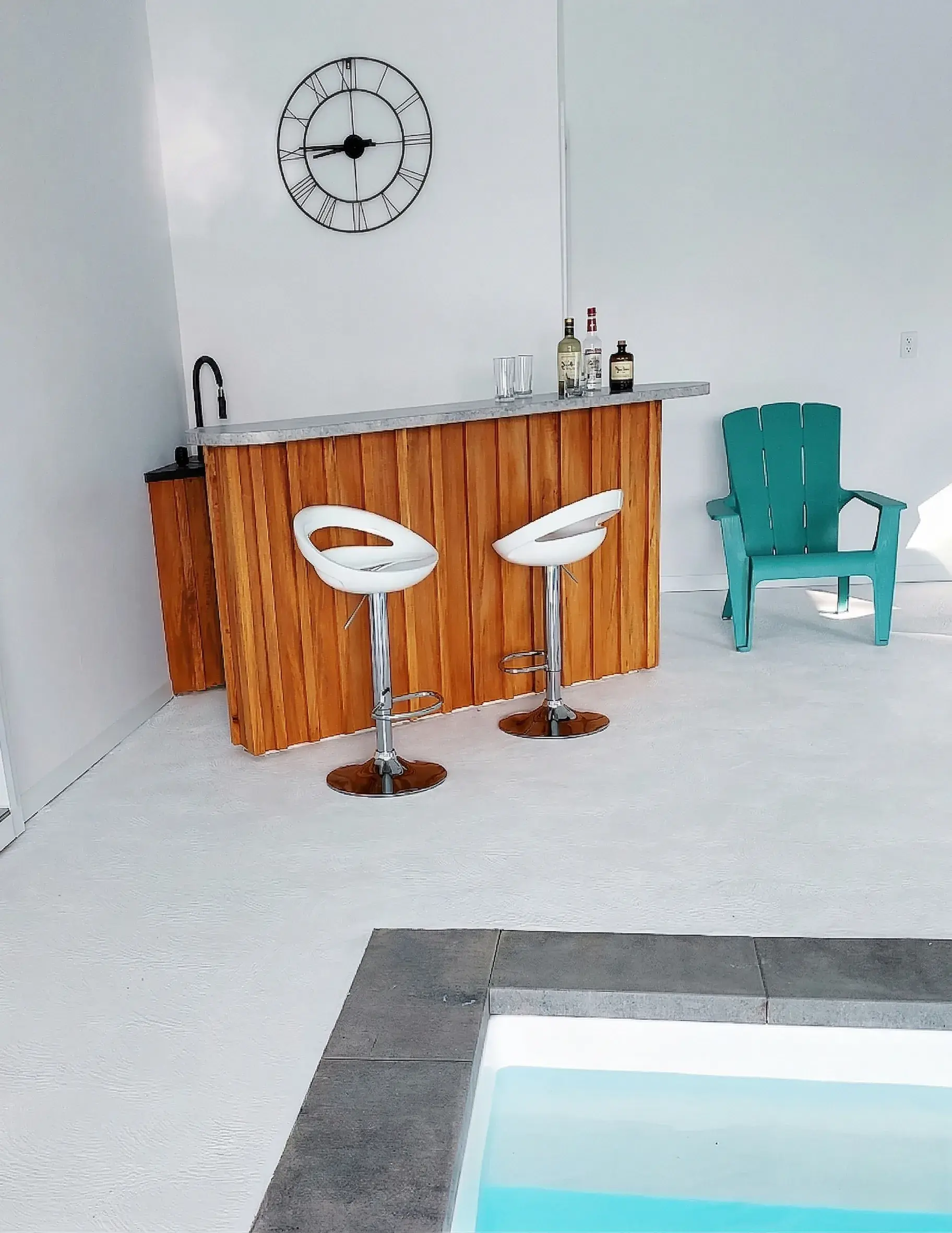 Coin bar en bois avec tabourets au bord de la piscine intérieure