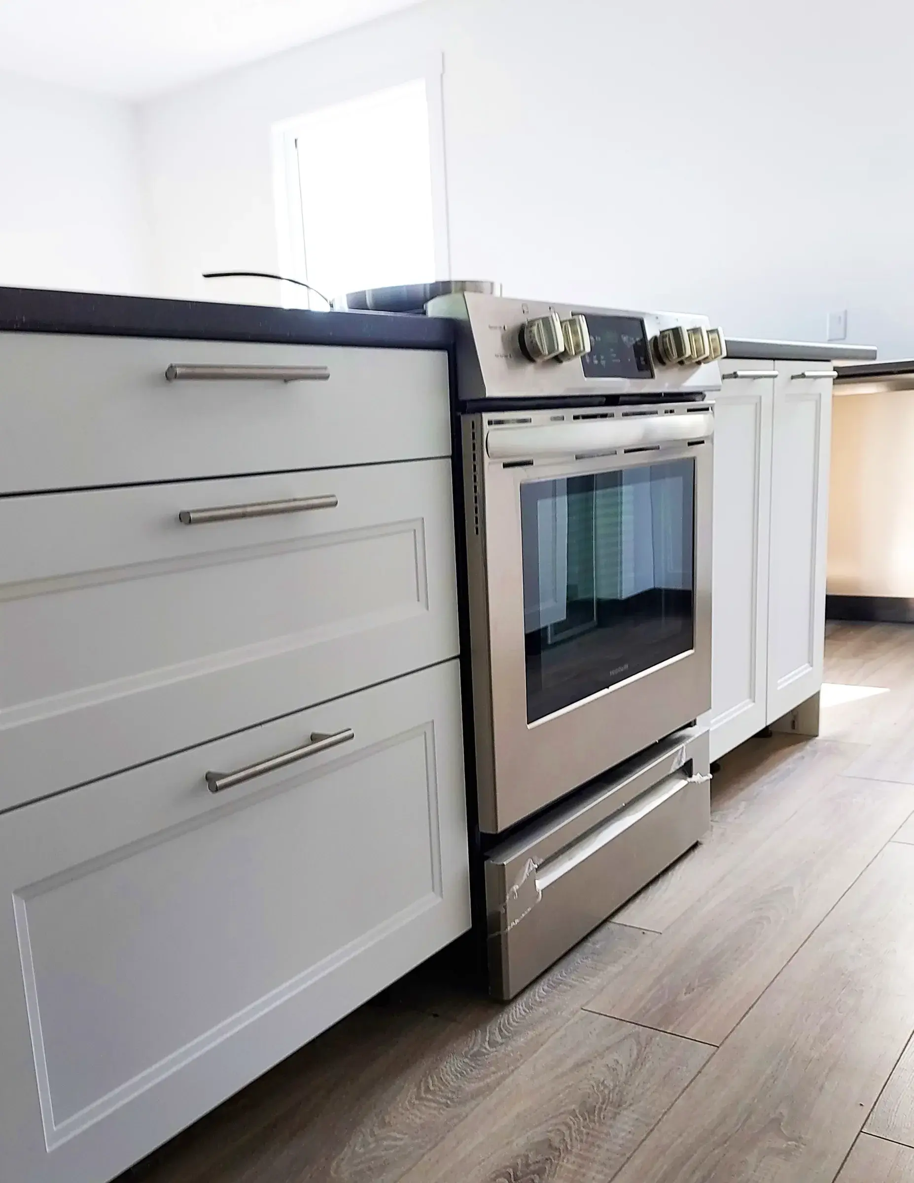 Cuisinière et four inox encastrés dans les armoires blanches