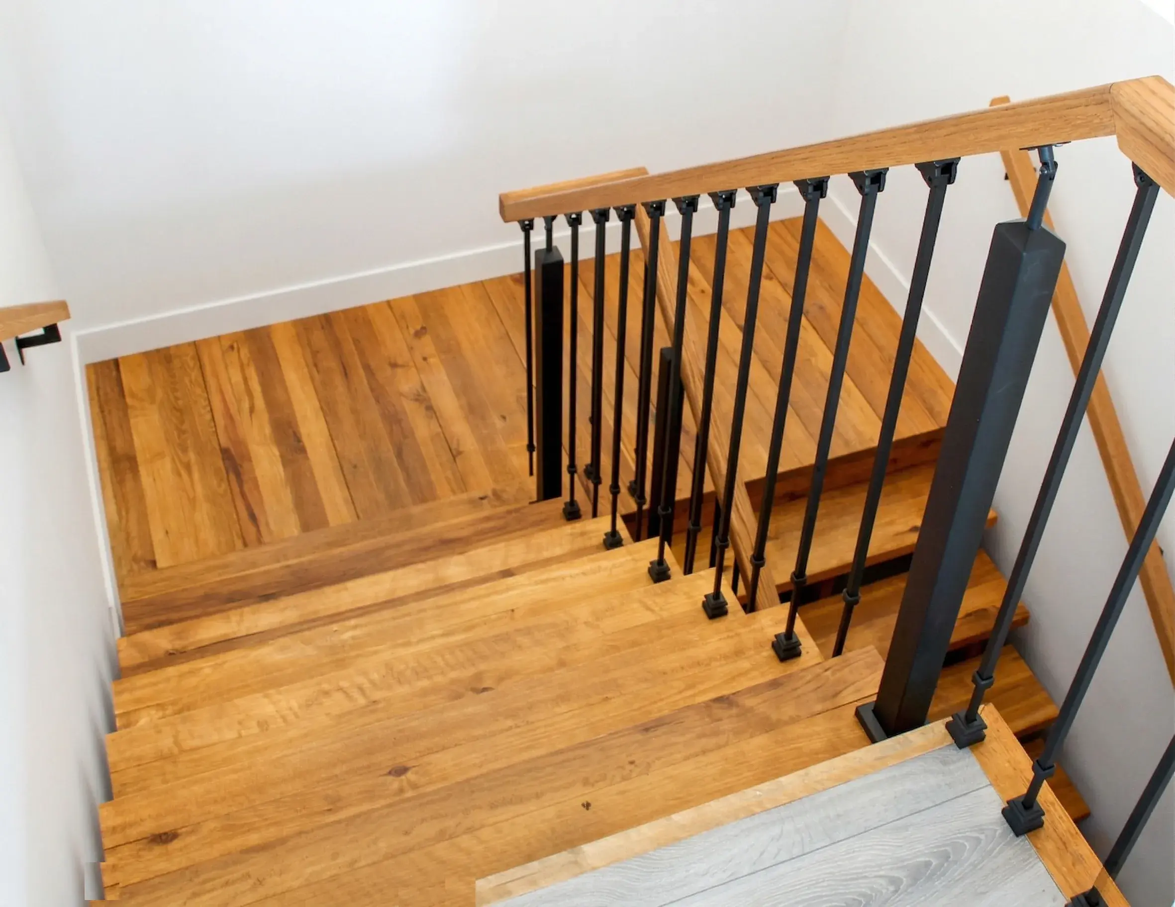 Escalier en bois avec rampe et barreaux de métal noir