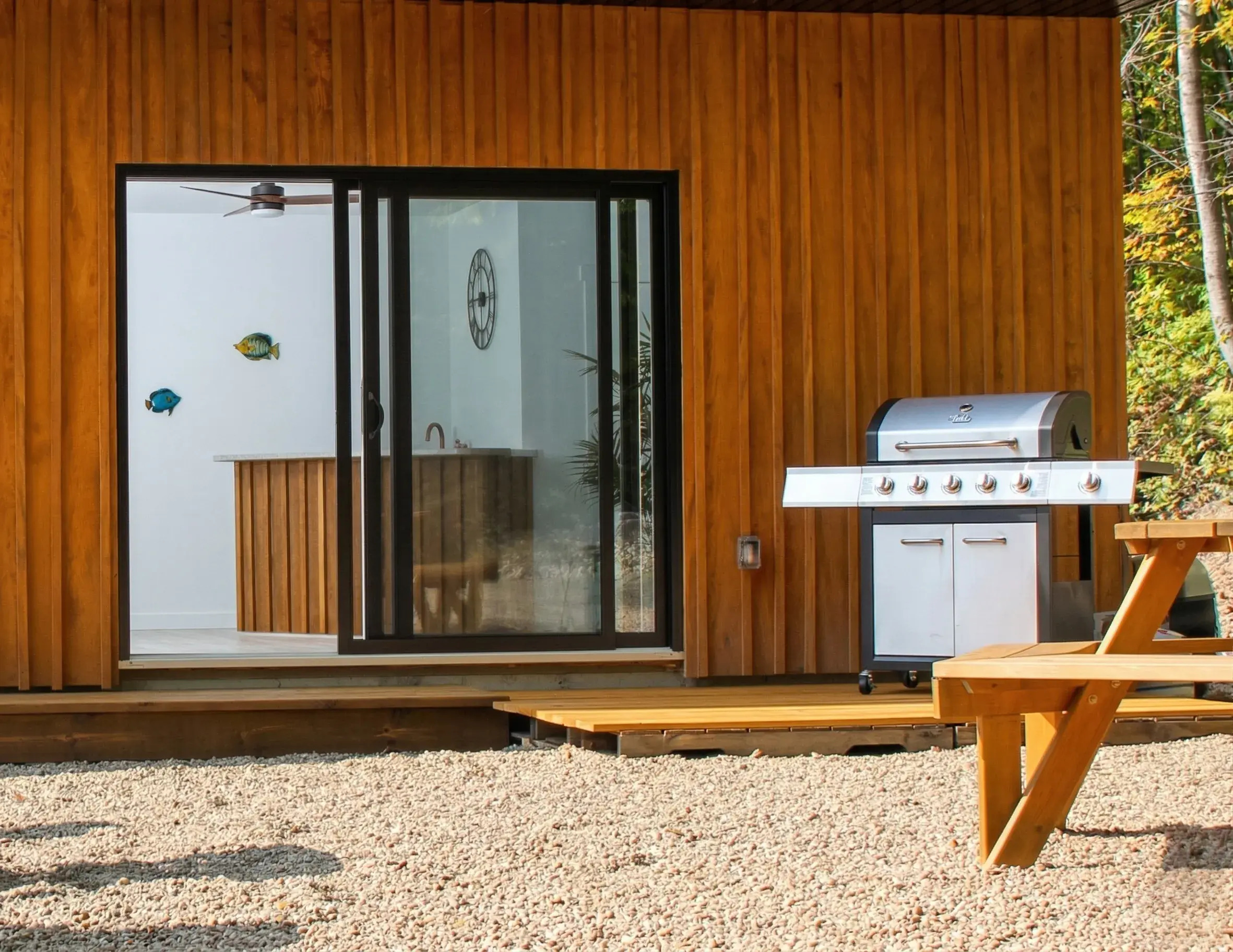 Façade en bois du chalet avec terrasse, BBQ et table de pique-nique