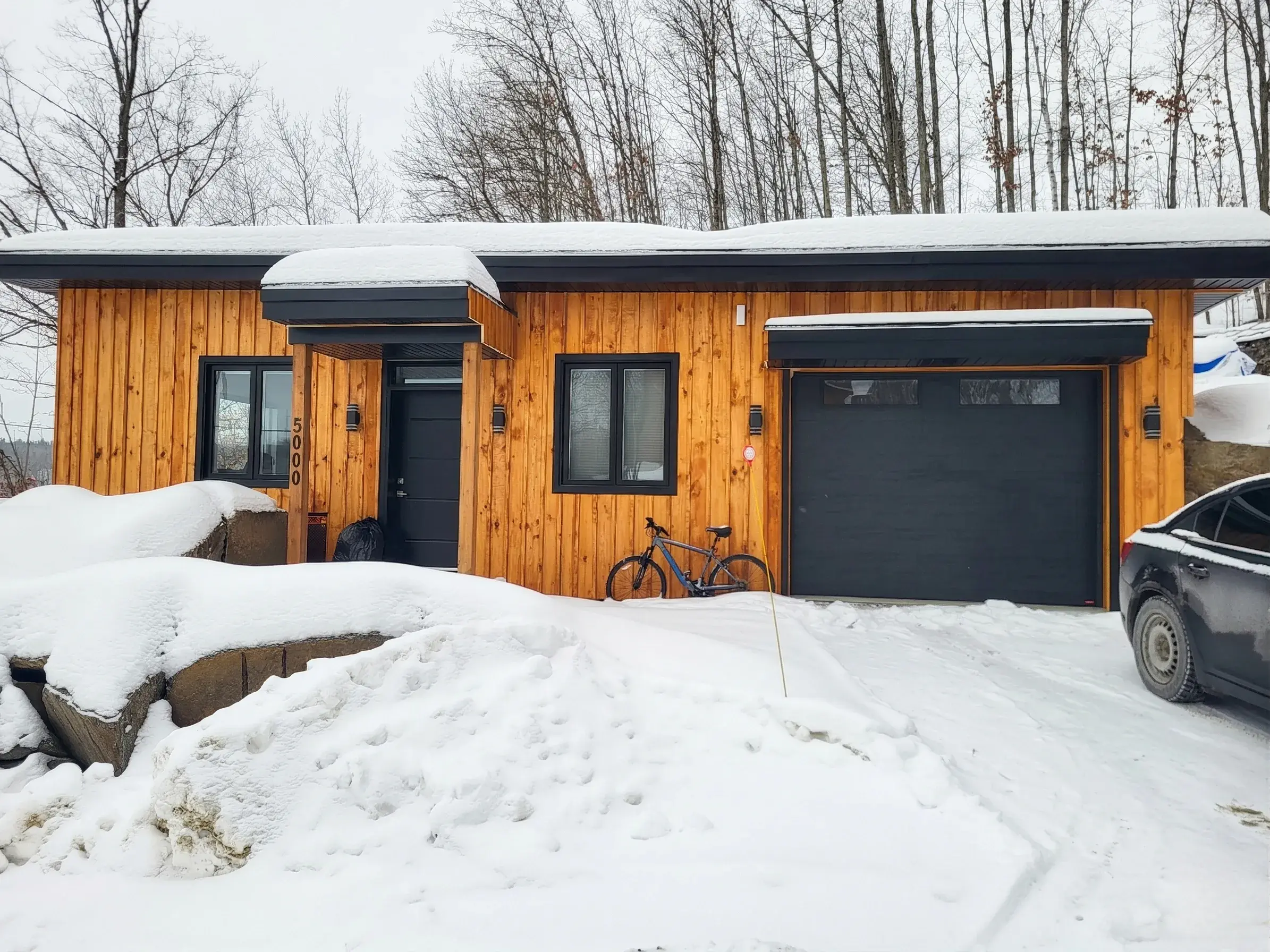 Façade avant du chalet et garage sous la neige en hiver