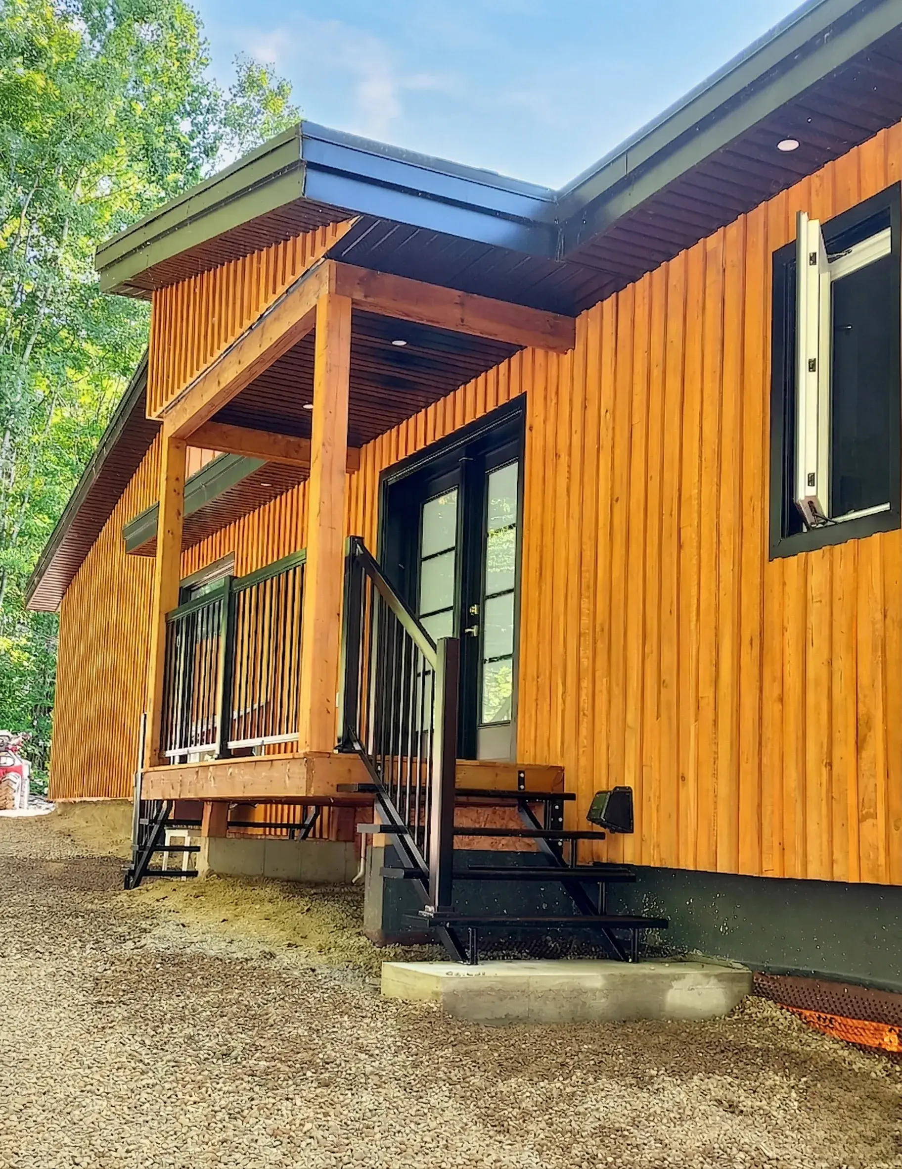 Côté du chalet en bois avec terrasse couverte et escalier extérieur