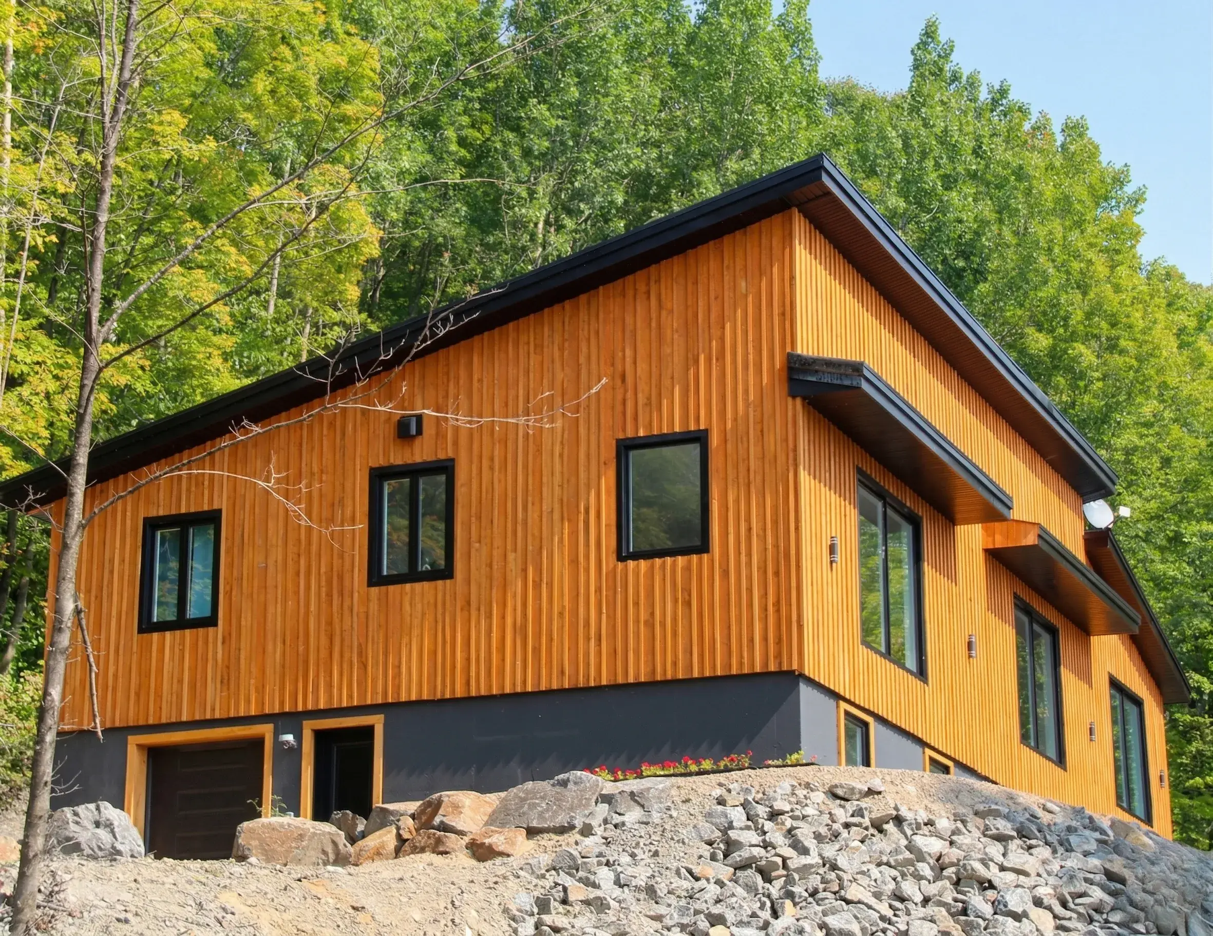 Façade du chalet en bois clair entourée de forêt en été