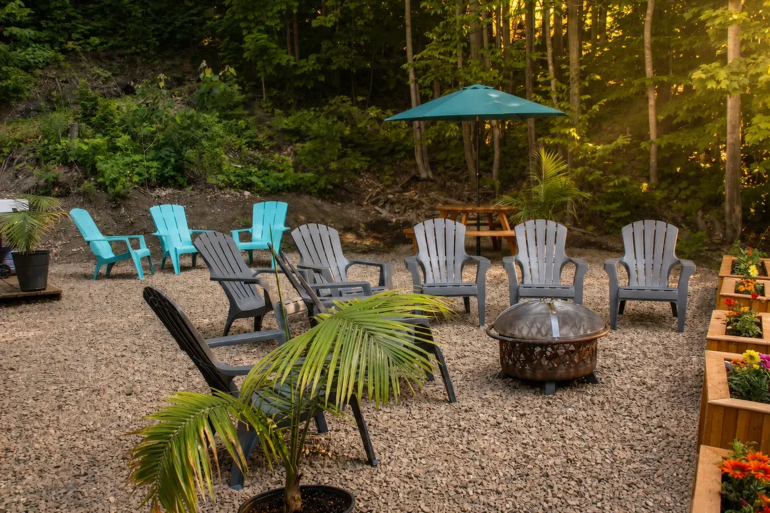 Aire de feu de camp en forêt avec chaises Adirondack, parasol et jardinières fleuries
