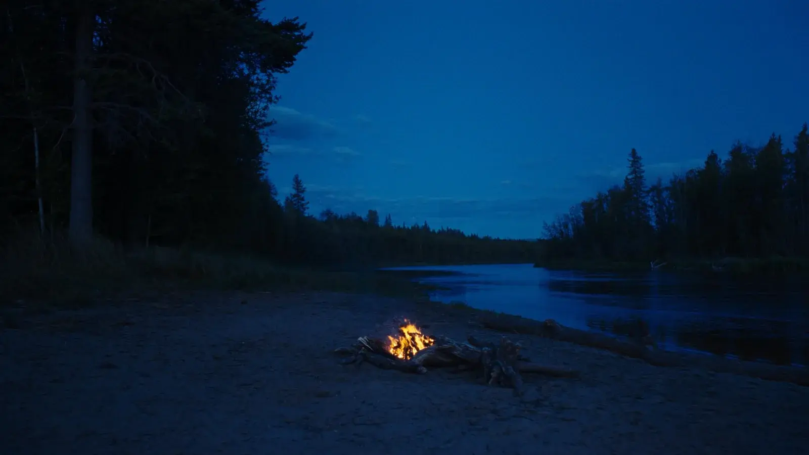 Feu de camp au bord de la rivière à la tombée du jour